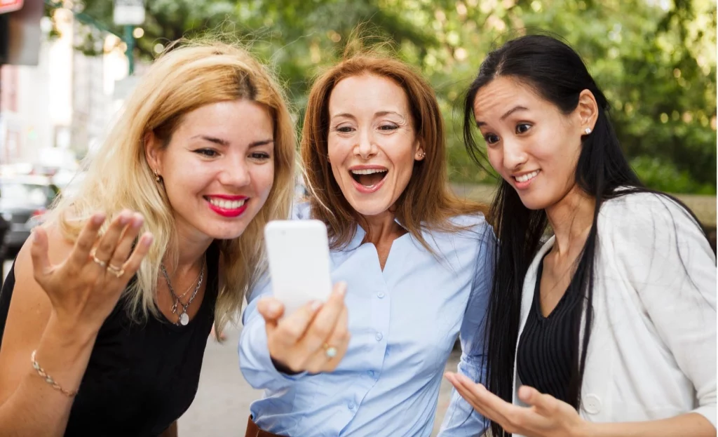 Drei Kolleginnen schauen sich auf dem Handy etwas an